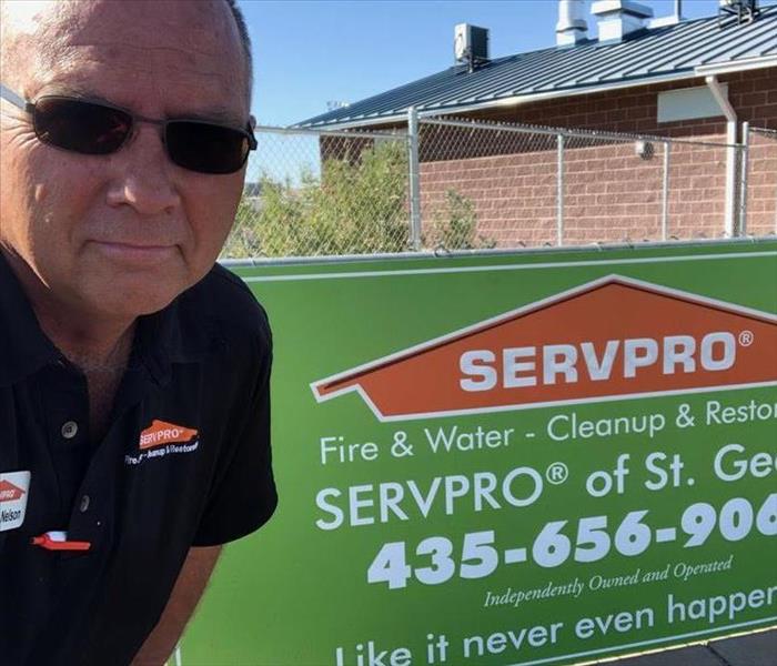 a man standing next to a sign that says SERVPRO of St. George