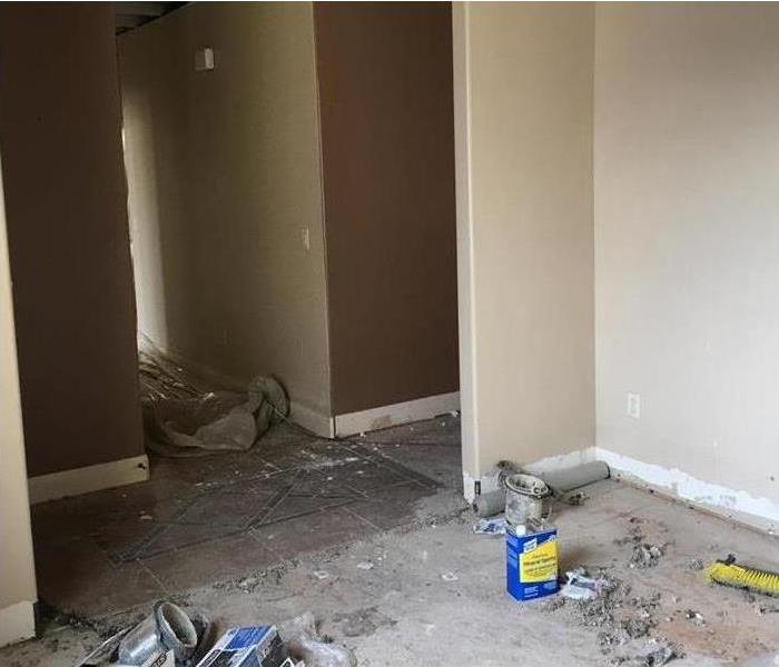 There are cans, plastic and dust on the floor of a home due to restoration from water damage