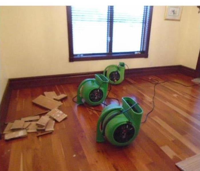 Machines drying water damage in a room of a home