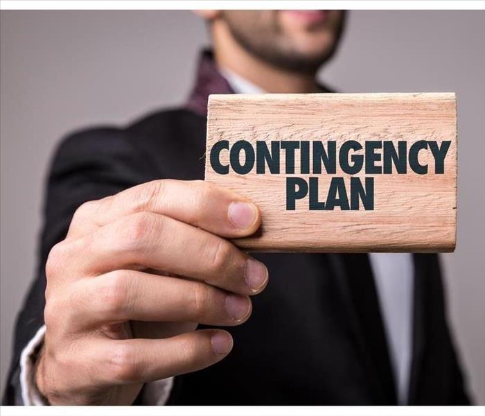 A man holding a piece of wood with the words Contingency Plan